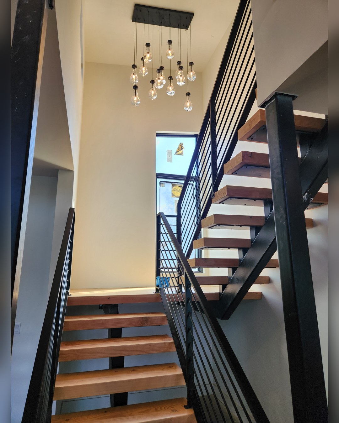 Floating stair with a steel rail and a two-storey window behind it