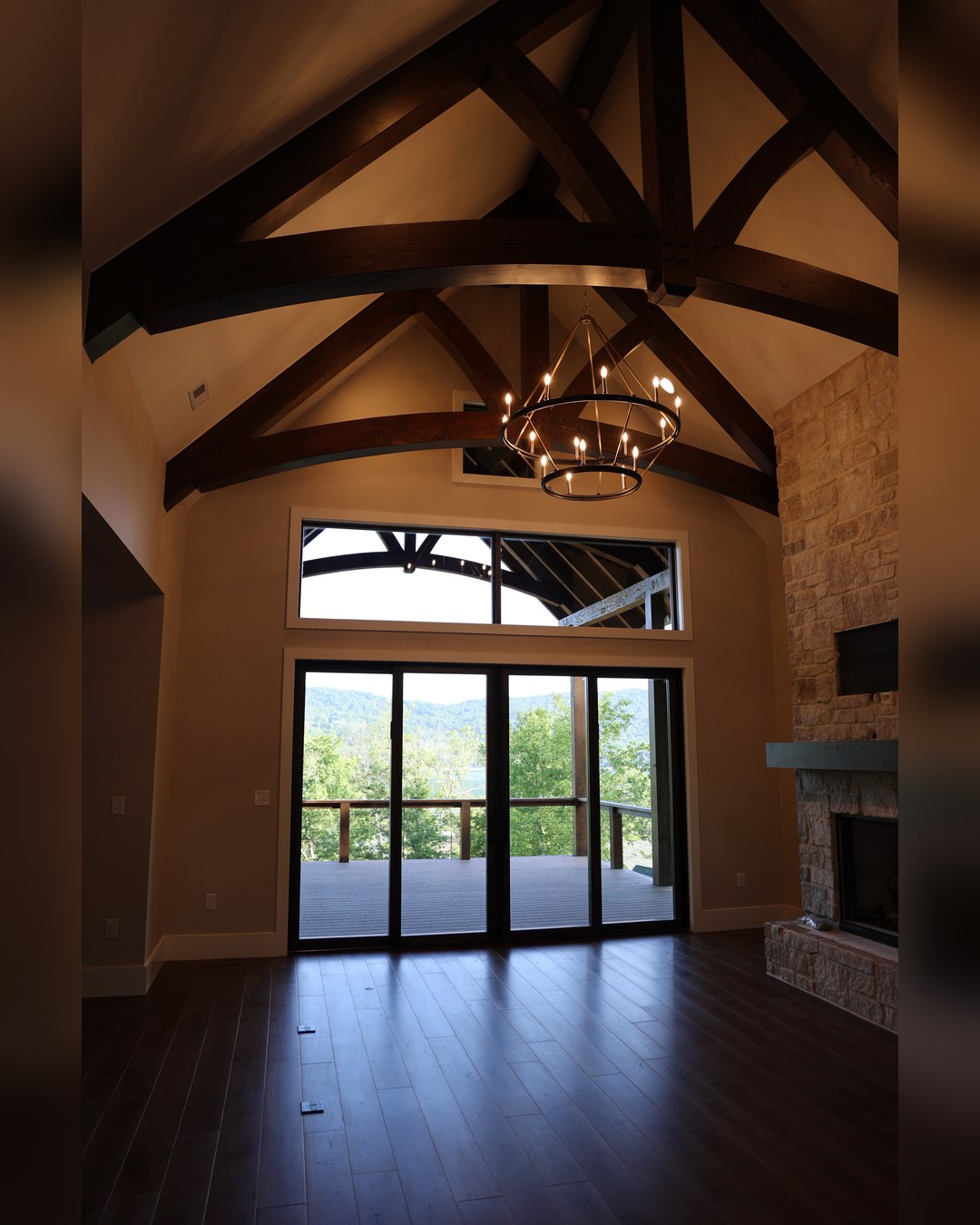 Great room with a stone fireplace, timber trusses and mountain views