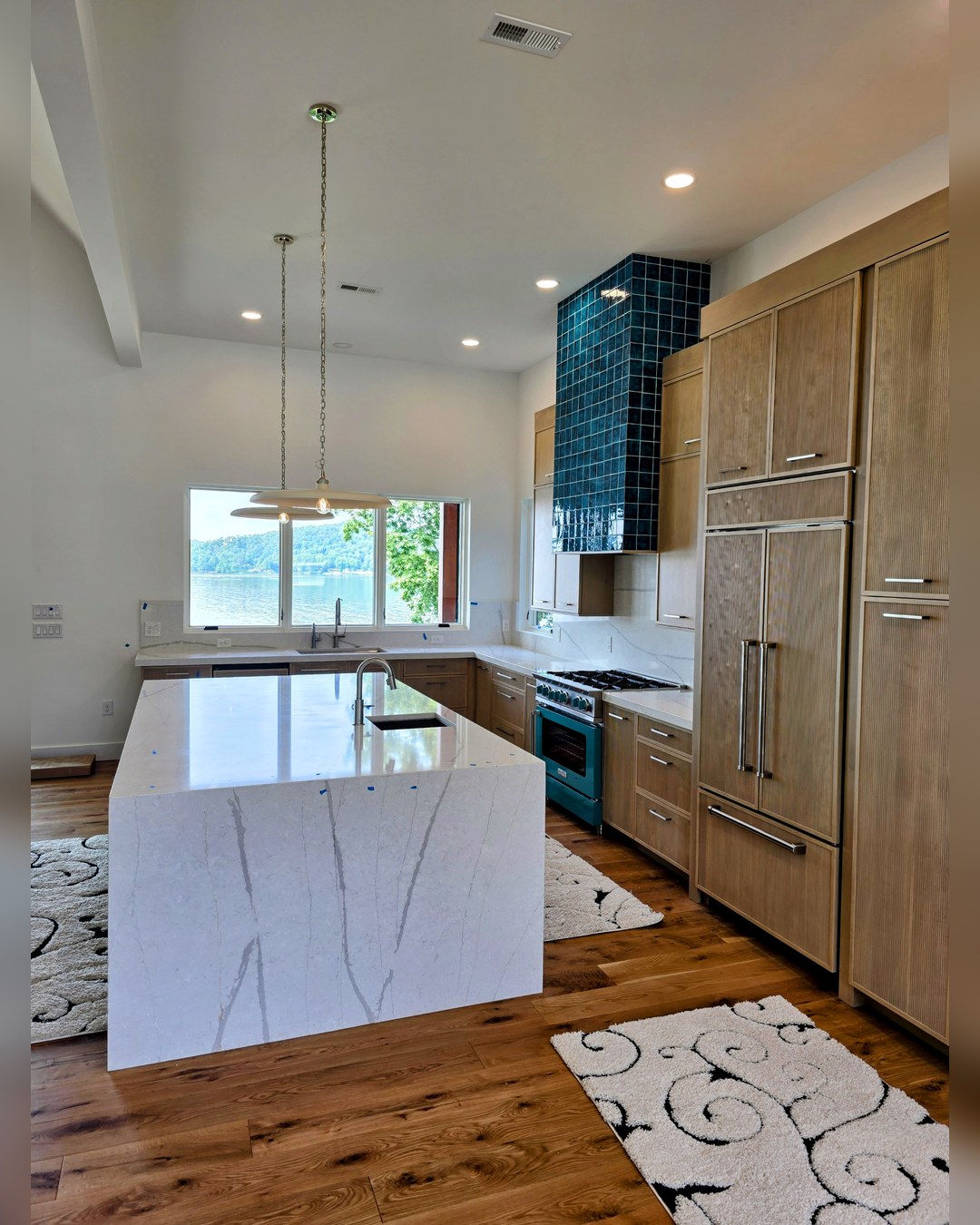 Kitchen with a quartz island, tile to the ceiling and a window over the sink facing the water